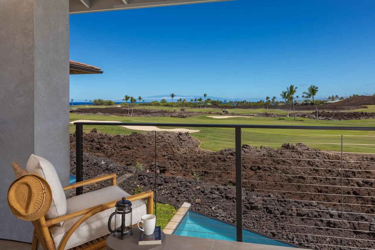 A covered patio overlooks a small pool, rocky ground, and a green landscape.