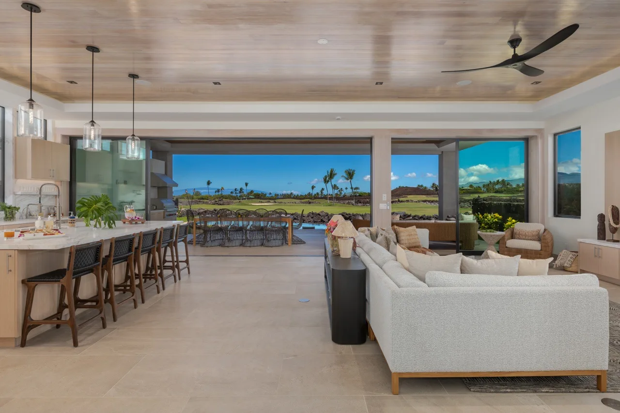 An open-plan living room and kitchen with wide windows overlooking a golf course.