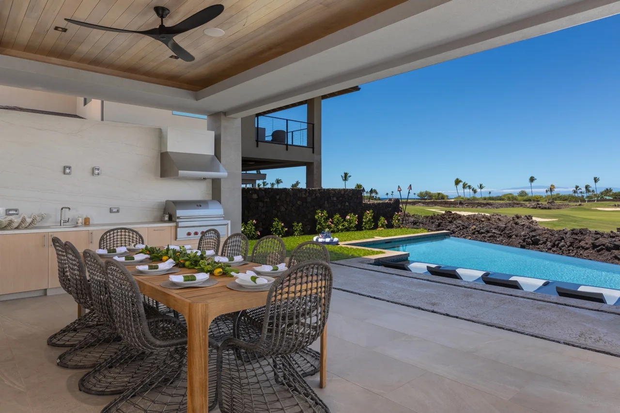 An outdoor dining area beside a swimming pool, with a table and woven seating.