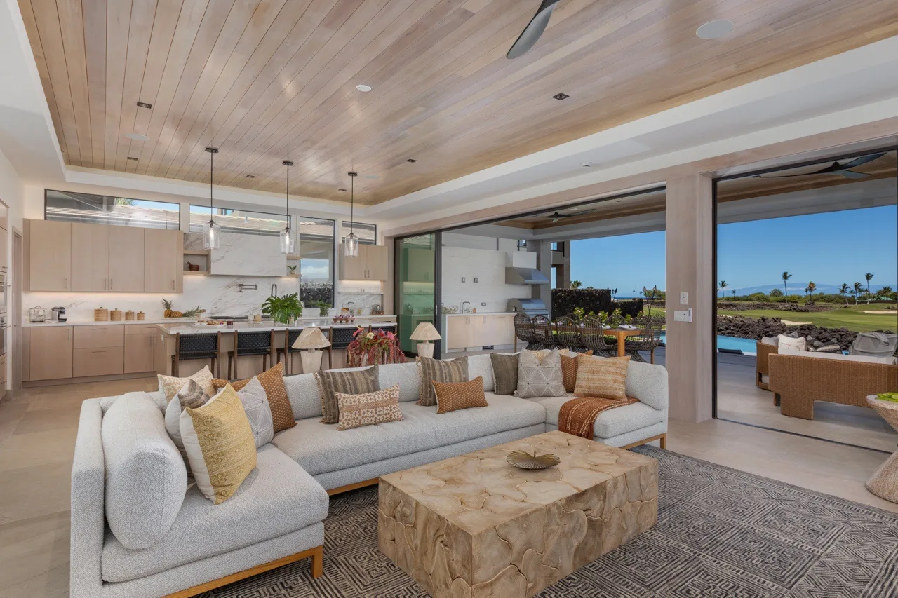 A bright living room opens onto a patio, with a large sectional and coffee table.