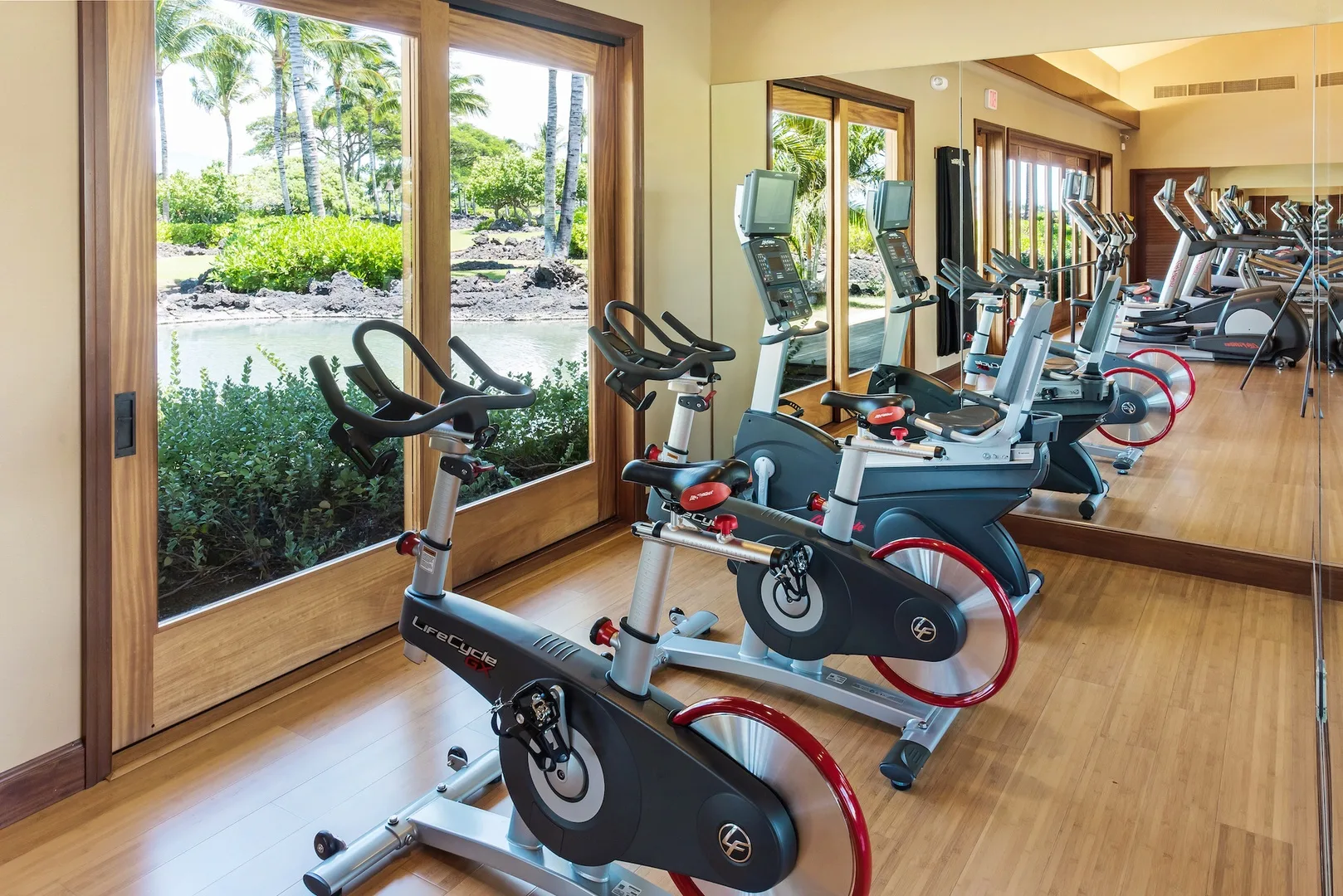A fitness room with stationary exercise bikes beside large windows.