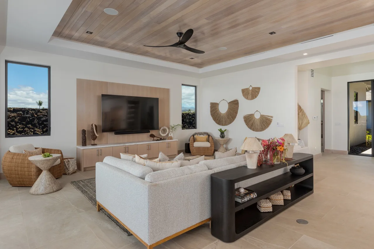 A bright living room with a large television and seating around a coffee table.