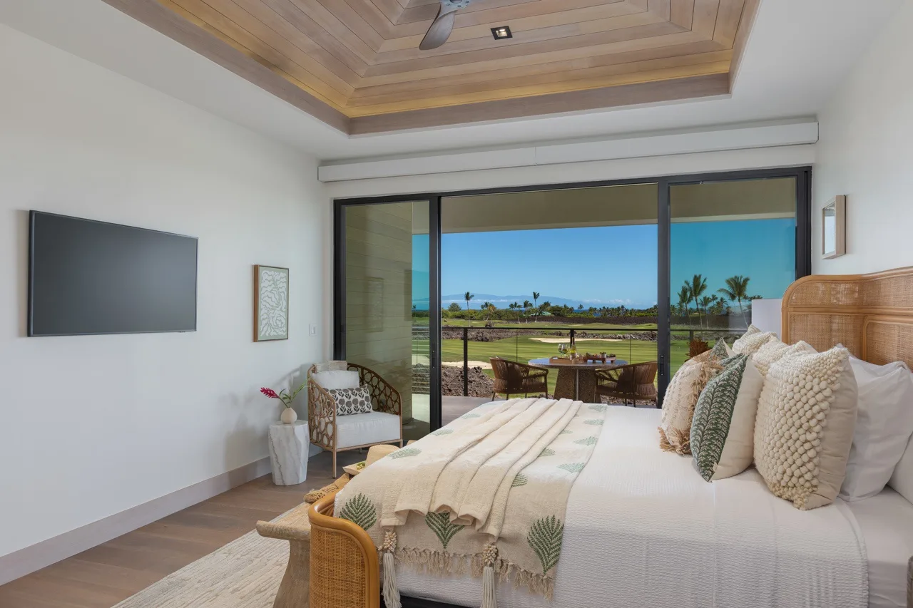A bedroom opens through sliding glass doors onto a terrace with ocean views.