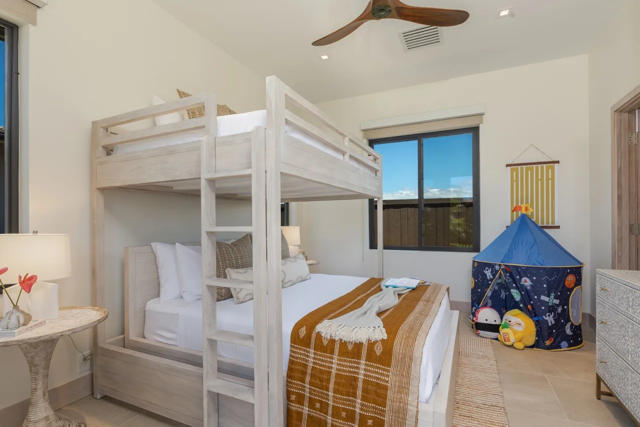 A bedroom with a wooden bunk bed, lower bed, and blue play tent.
