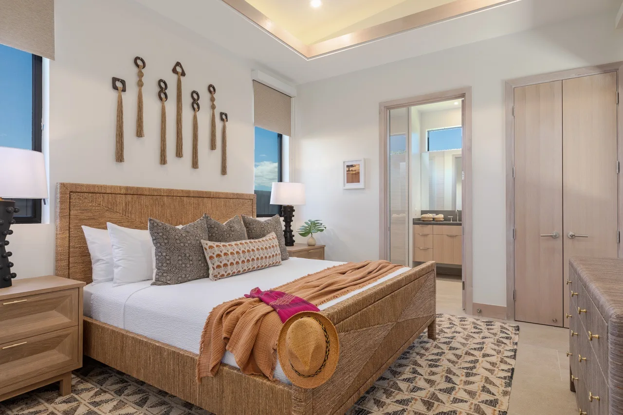 A bedroom with a bed, layered pillows, and a woven headboard.