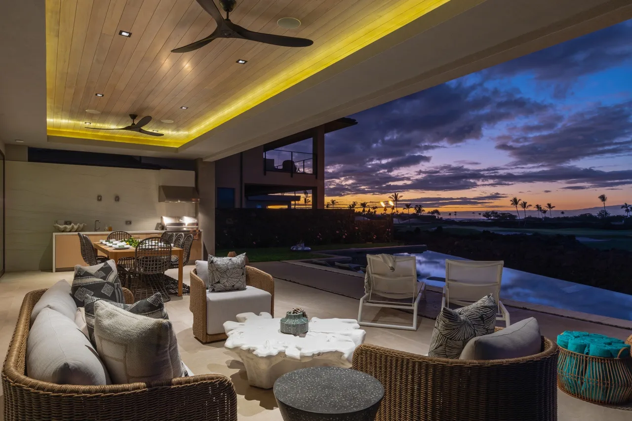 An outdoor lounge beside a pool overlooks the sunset sky.
