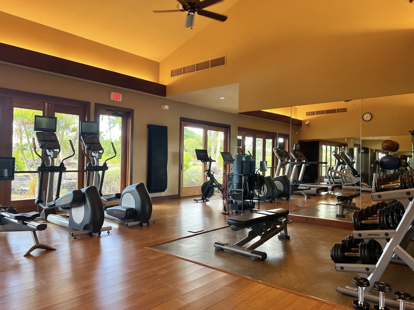 A fitness room with exercise machines, weights, and mirrored walls.