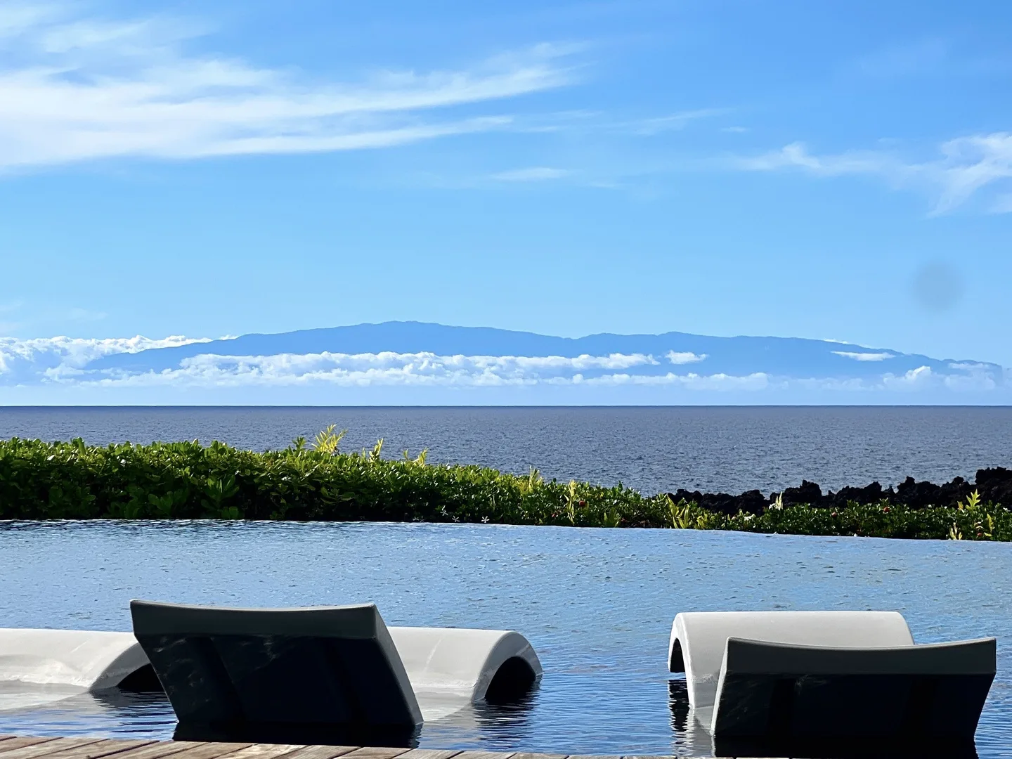 An infinity pool overlooks the ocean and a distant mountain range.