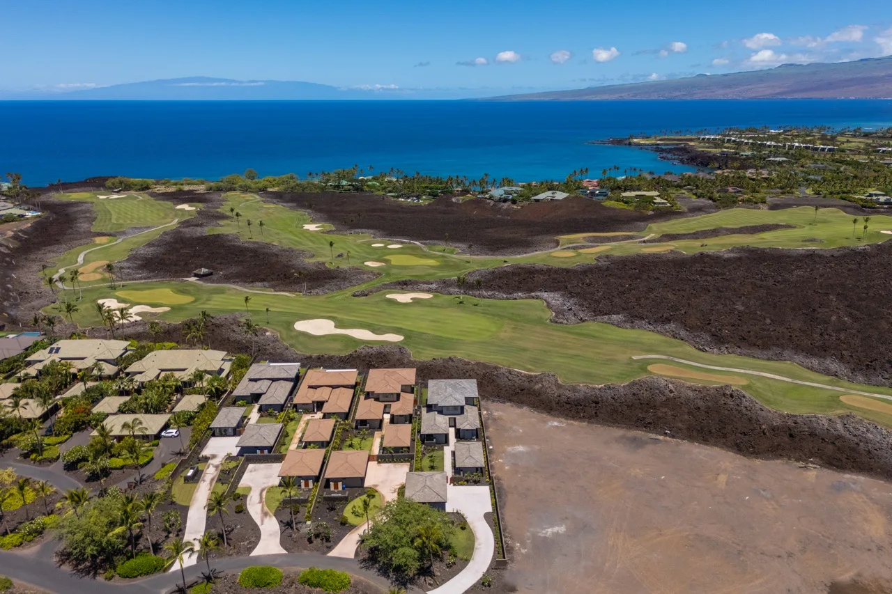 An aerial view of a coastal golf course with homes in the foreground.