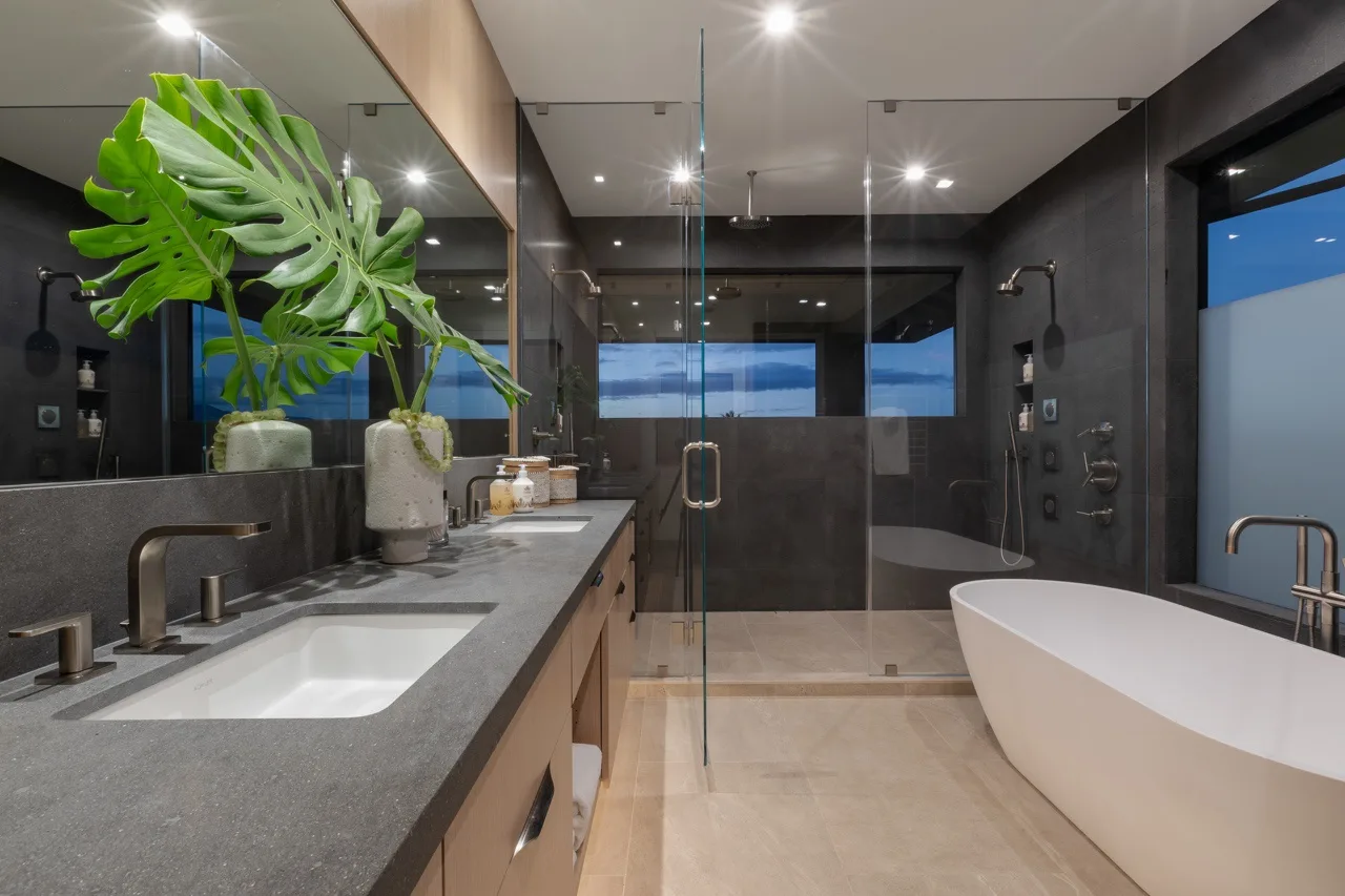 A modern bathroom with a double vanity, glass shower, and freestanding tub.