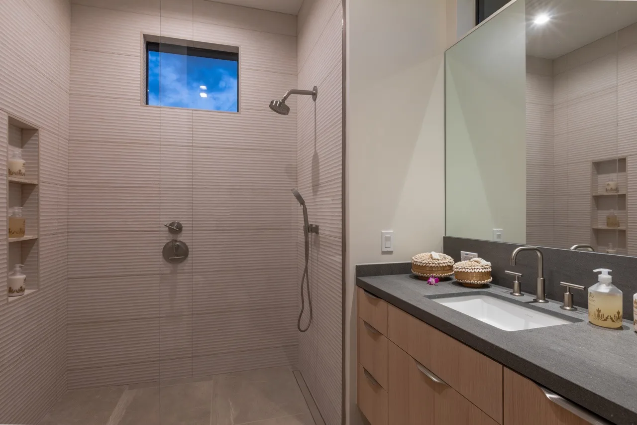 A tiled bathroom with a walk-in shower and a vanity with a sink.