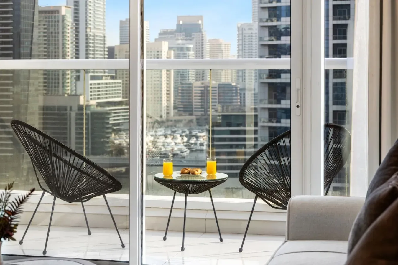 A balcony seating area overlooks a city skyline, with a small table between two chairs.