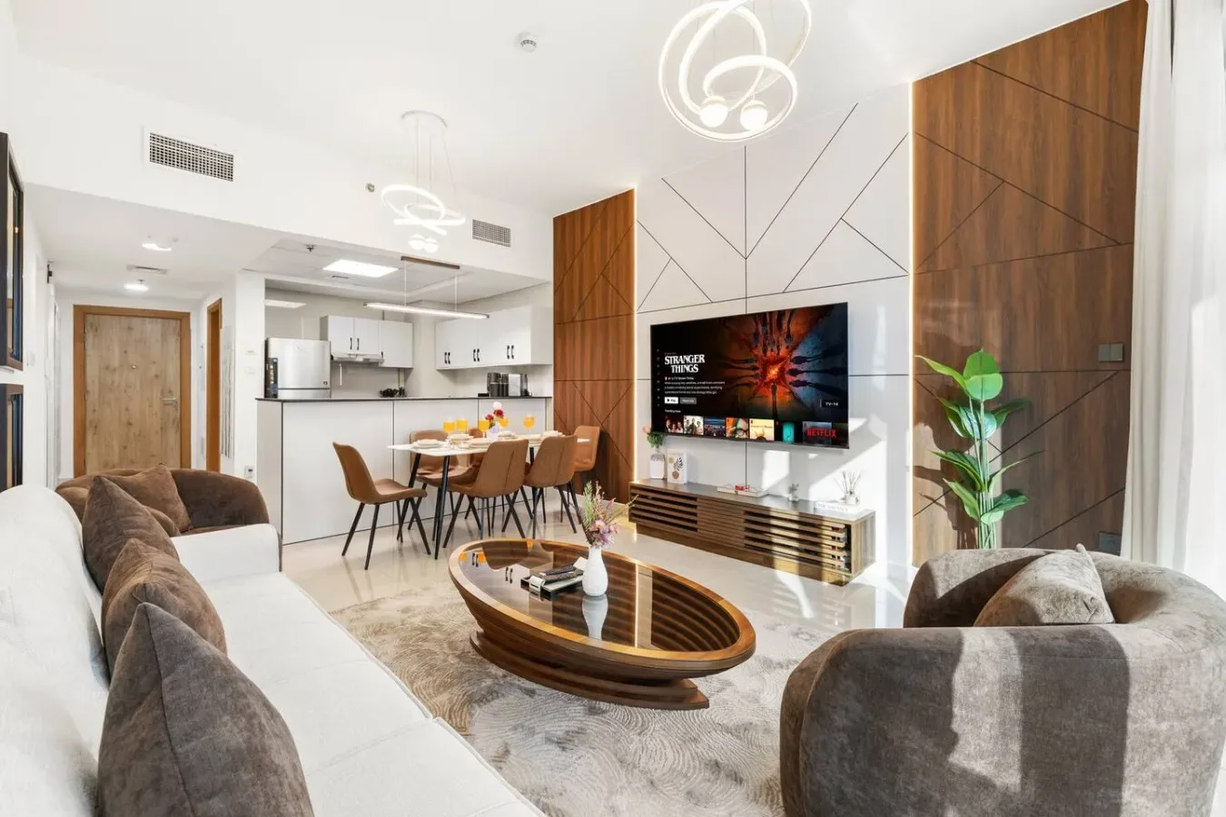 A modern living room opens onto a dining area and kitchen.