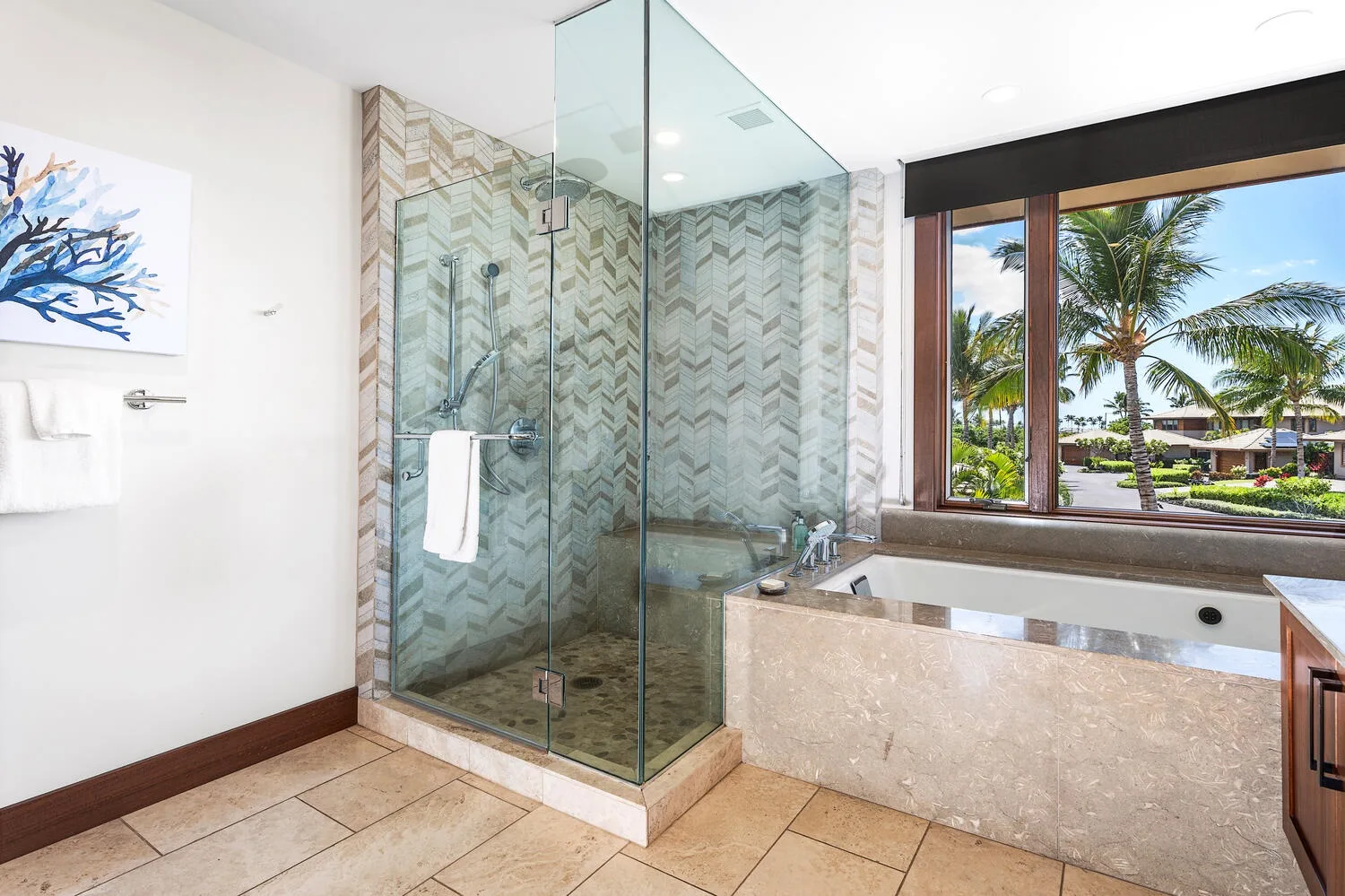 Un baño luminoso cuenta con una ducha de vidrio y una bañera grande junto a una ventana.