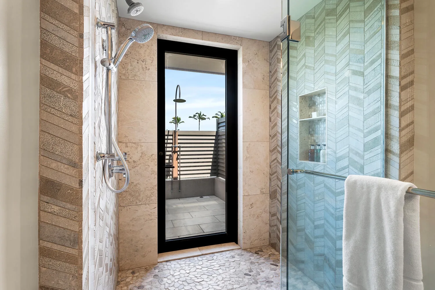 Un baño revestido de azulejos, con ducha de vidrio y una puerta que da a un balcón.