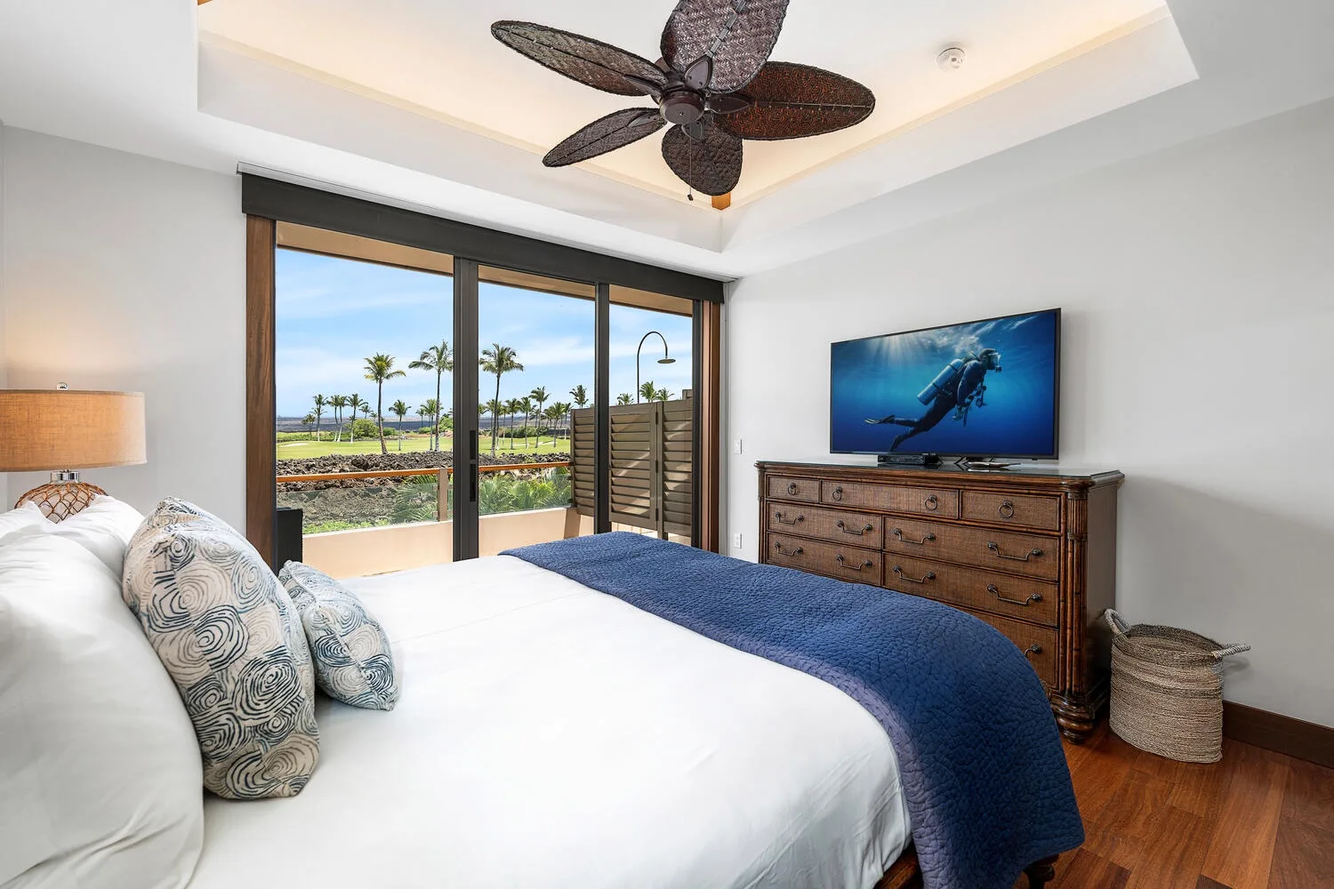 Un dormitorio con una cama frente a puertas corredizas de vidrio y una cómoda con un televisor.
