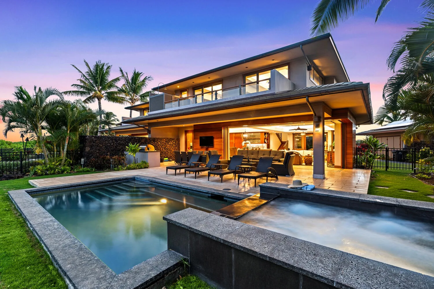 A modern house opens onto a swimming pool and outdoor seating area.