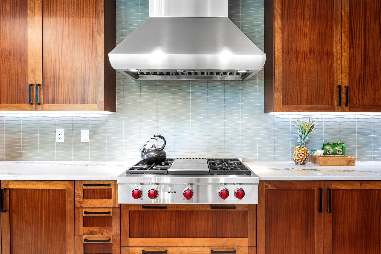Una cocina con una estufa bajo una campana extractora de acero inoxidable.