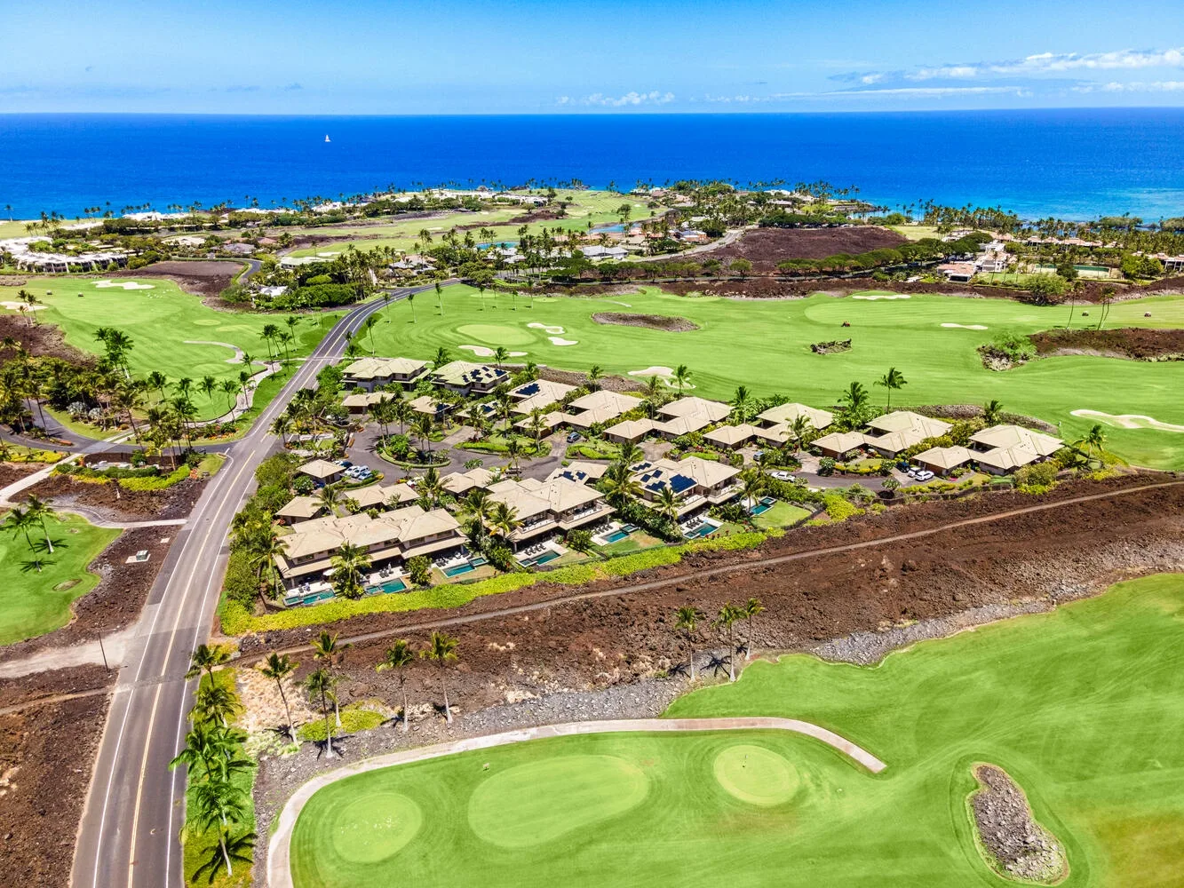 Vista aérea de un campo de golf costero con viviendas y el océano al fondo.