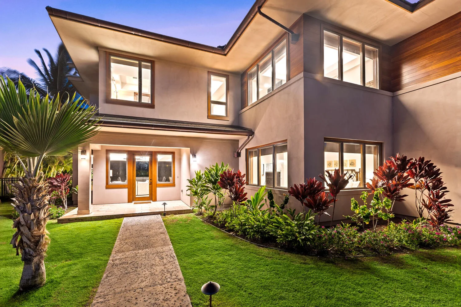 Una casa moderna de dos plantas con un sendero entre los jardines del frente.
