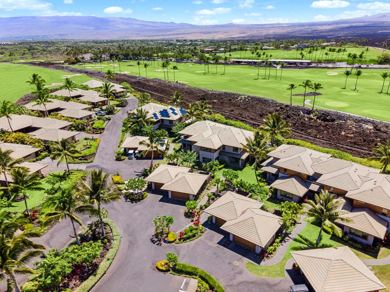 Vista aérea de un complejo residencial junto a un campo de golf verde.