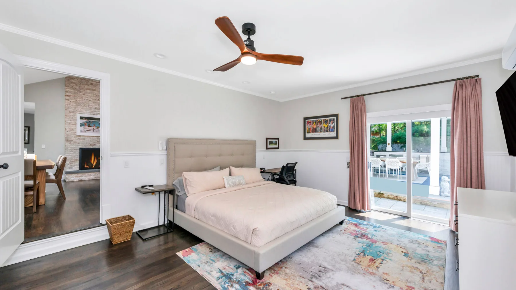 Un dormitorio con cama, ventilador de techo y puertas corredizas de vidrio que dan a un patio.