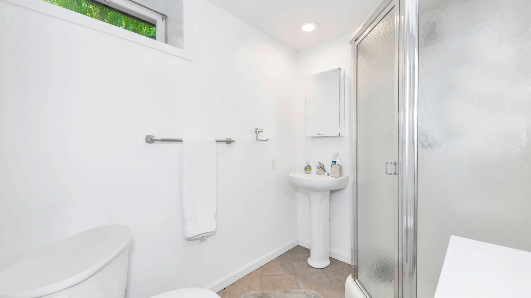Un baño luminoso con lavabo y ducha con mampara de vidrio.