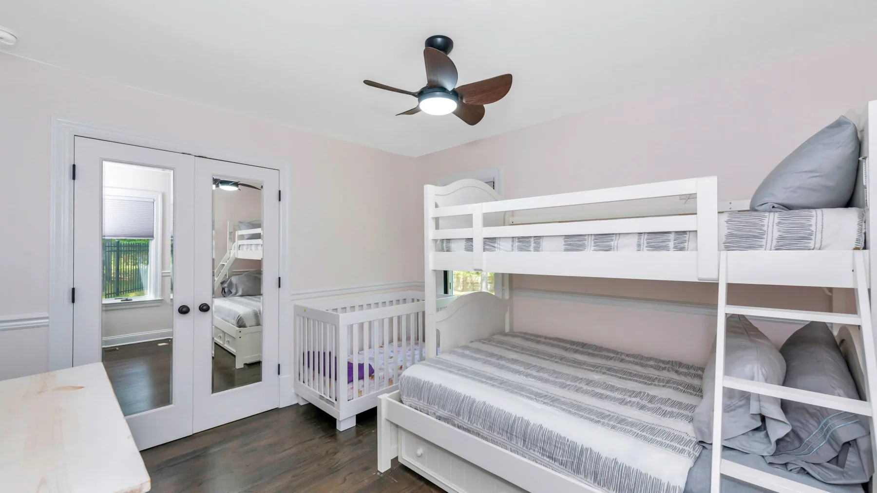 Un dormitorio con una litera blanca y una cuna pequeña al lado.