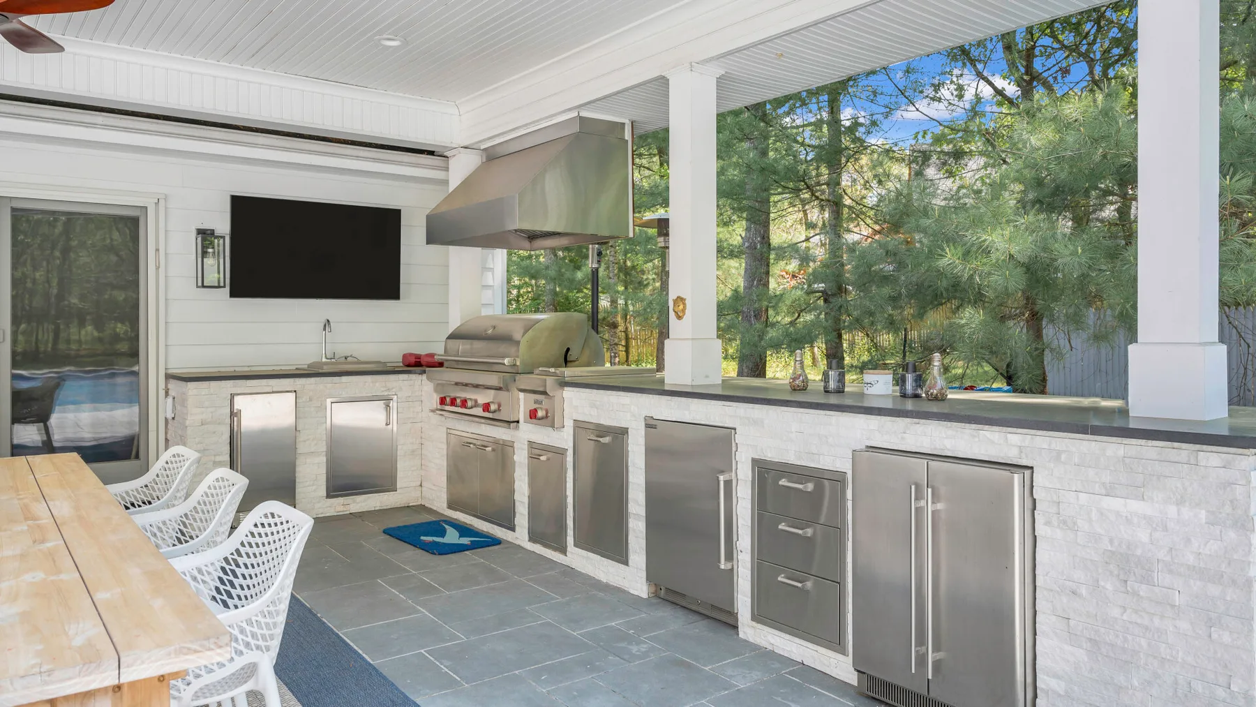 Una cocina exterior cubierta con una encimera larga y zona de asientos.