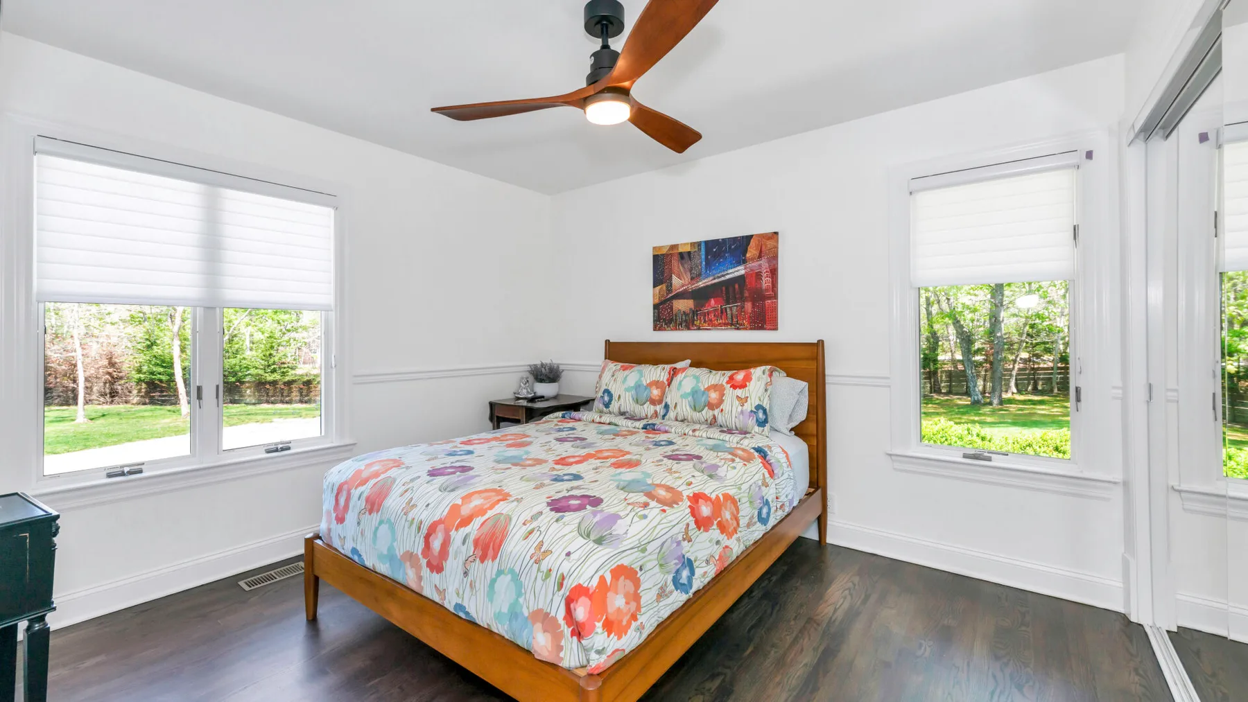 Un dormitorio luminoso con una cama de madera y ropa de cama floral colorida.