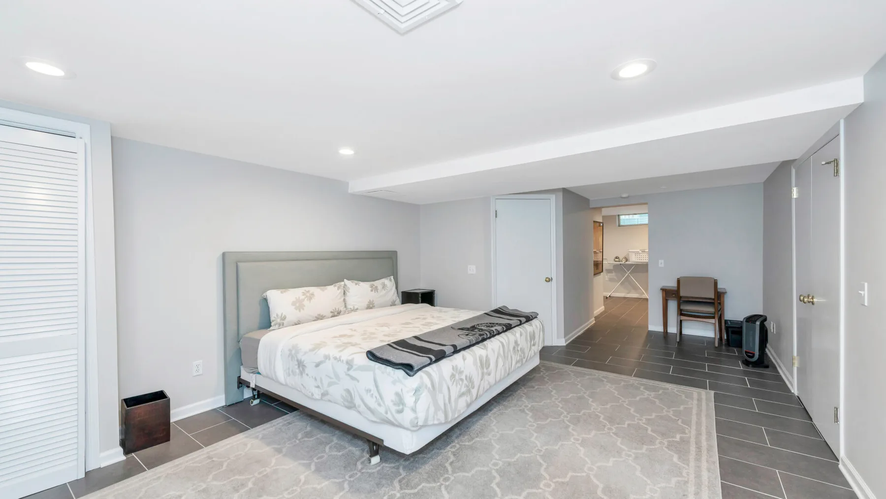 Un dormitorio con una cama y una pequeña zona de comedor visible a través de la puerta.