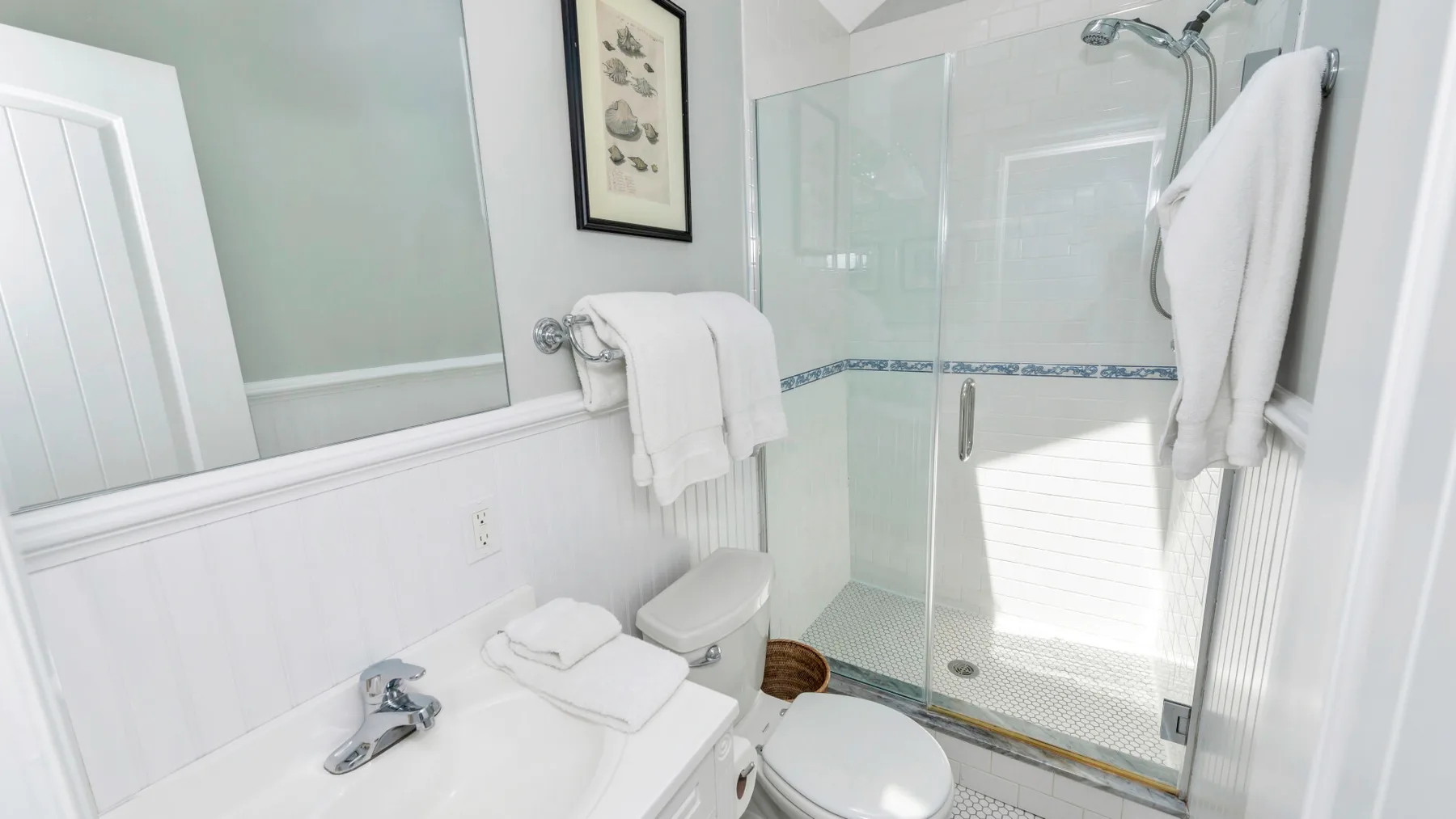 Un baño luminoso con lavabo, inodoro y ducha de vidrio.