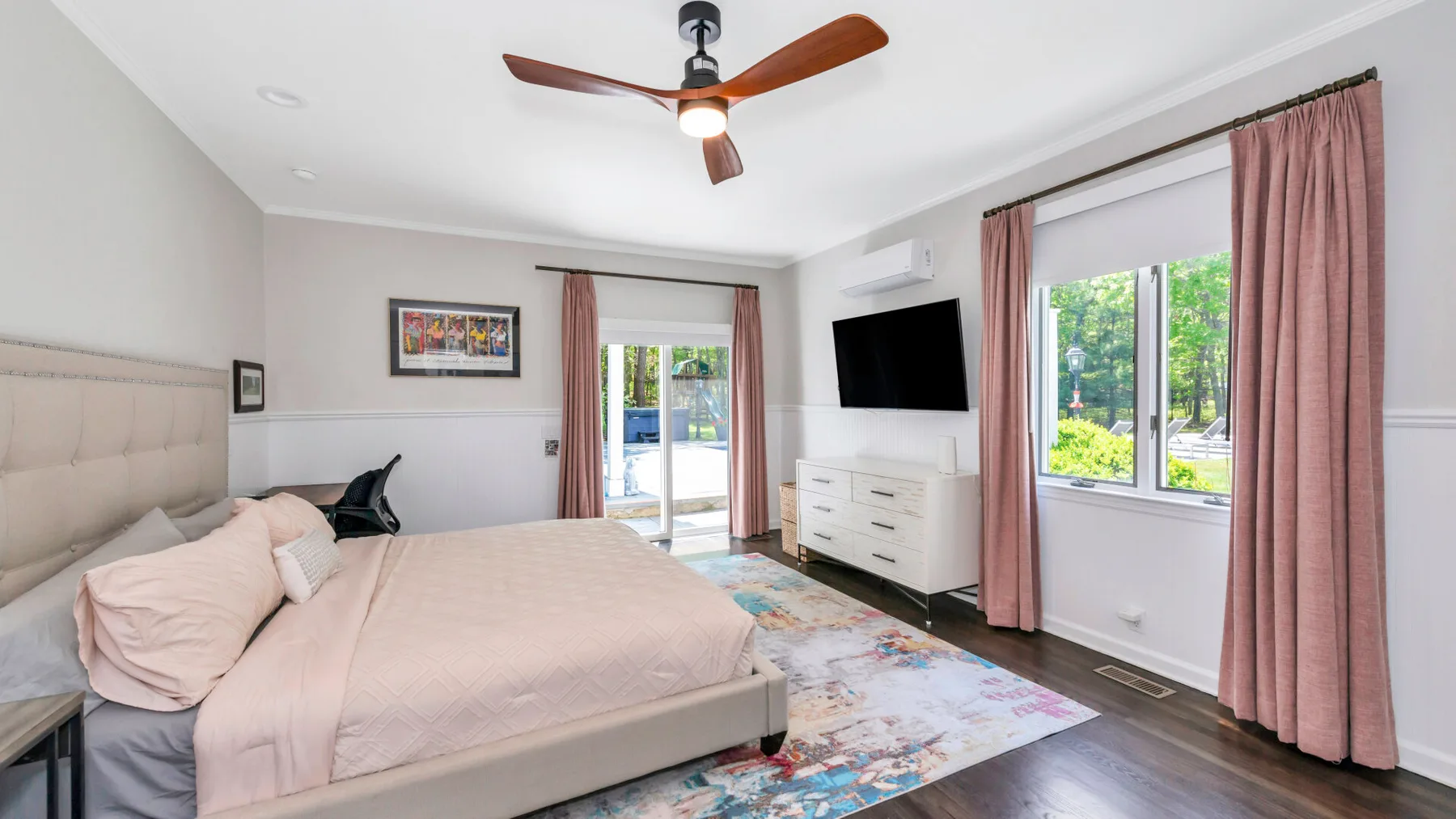 Un dormitorio luminoso con una cama grande, ventanas y un ventilador de techo.