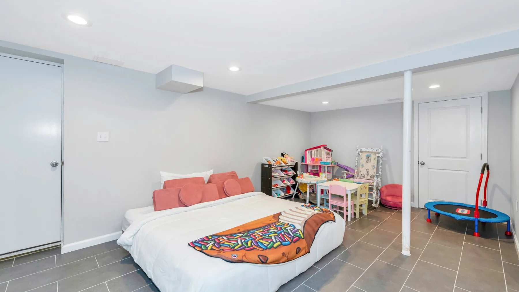 Un dormitorio luminoso con una cama y una colorida zona de juegos infantil.