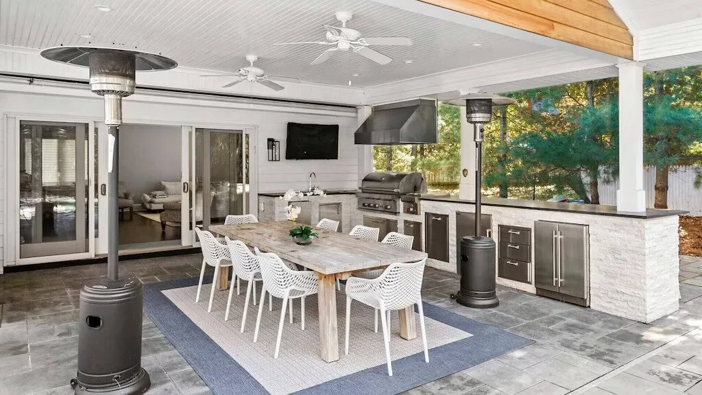 Comedor y cocina exterior cubiertos, con una mesa larga y una barra.