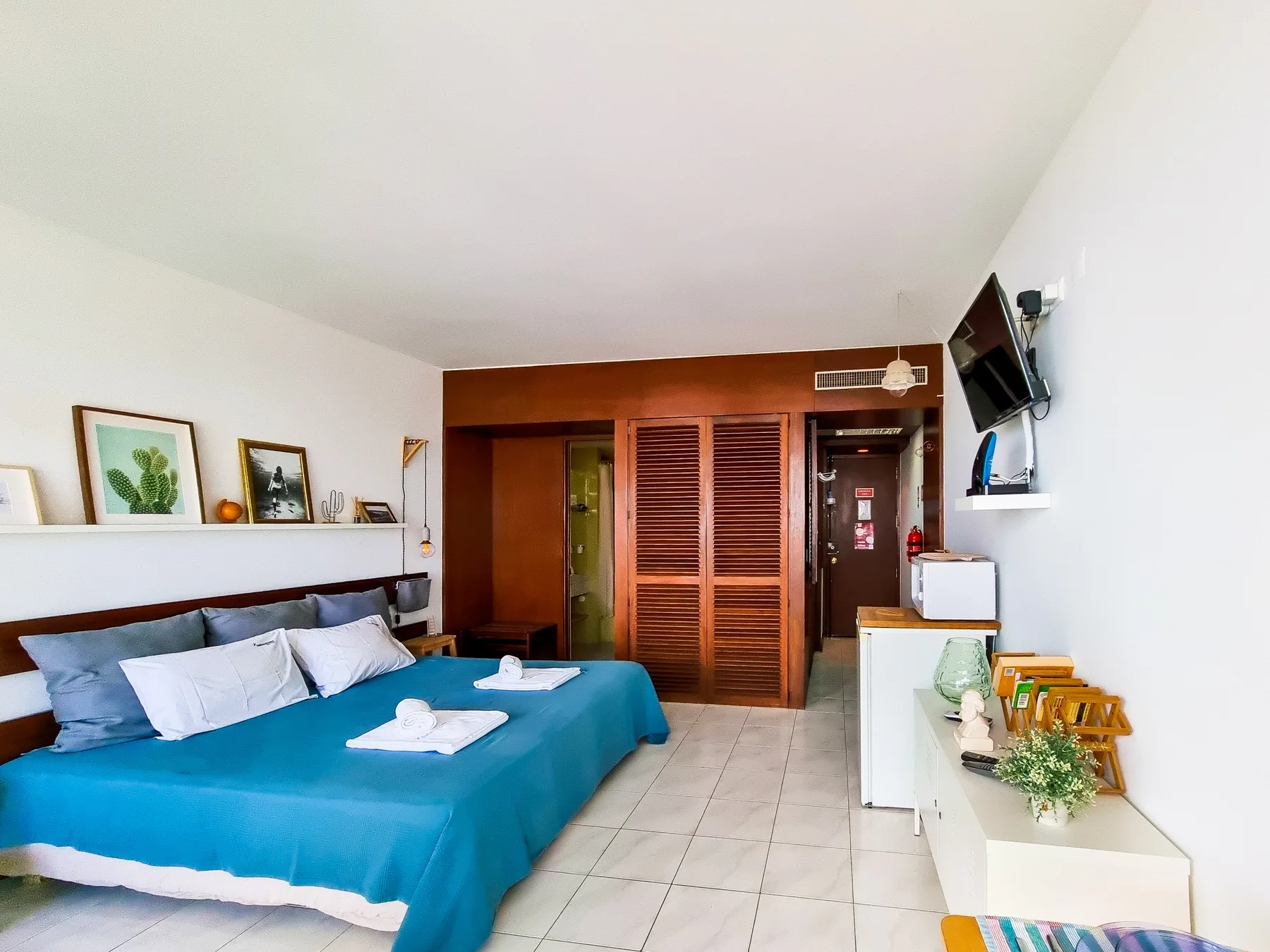 Un dormitorio tipo estudio con cama, suelo de baldosas y armario de madera.