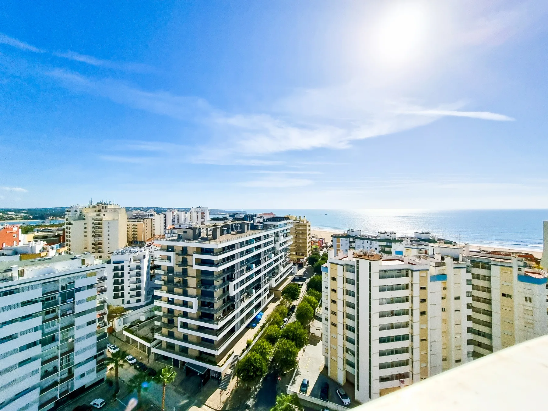 Vista elevada de una ciudad costera, con edificios y el mar al fondo.
