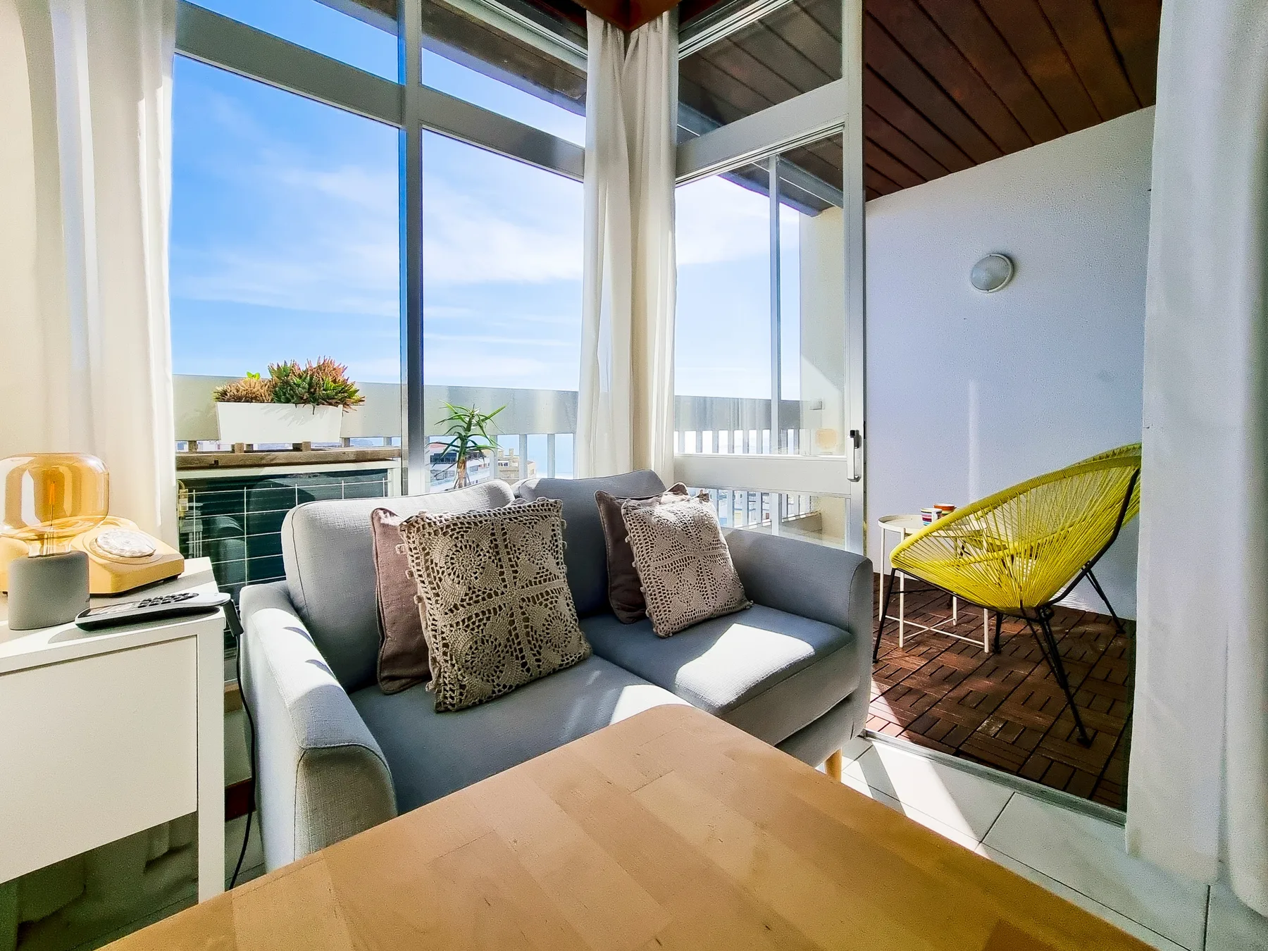 A bright living area with seating beside large windows and a balcony.