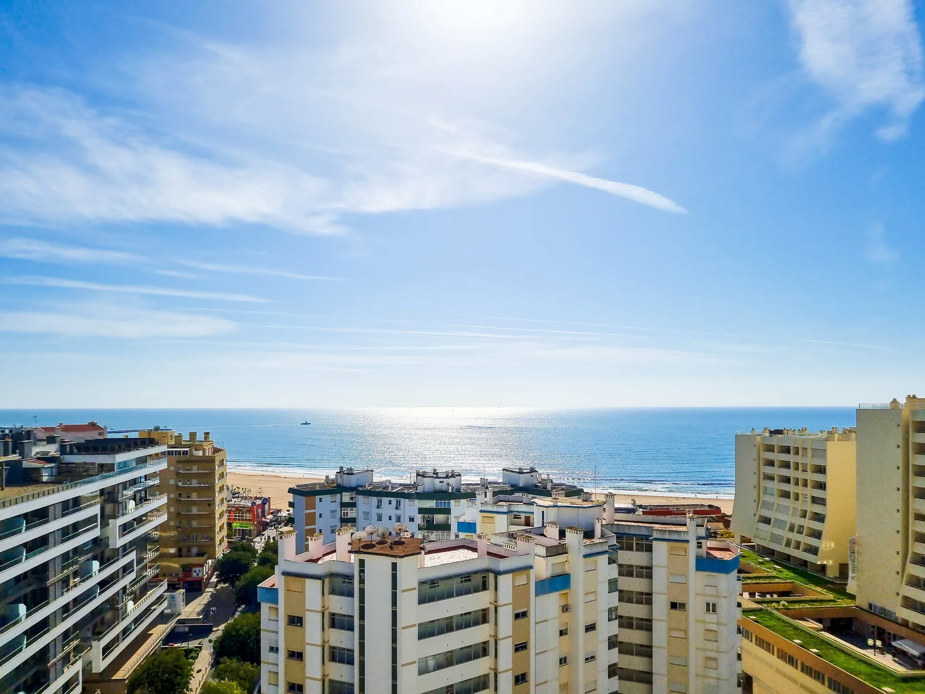 Un paisaje urbano costero con edificios de apartamentos frente al mar bajo un cielo azul.