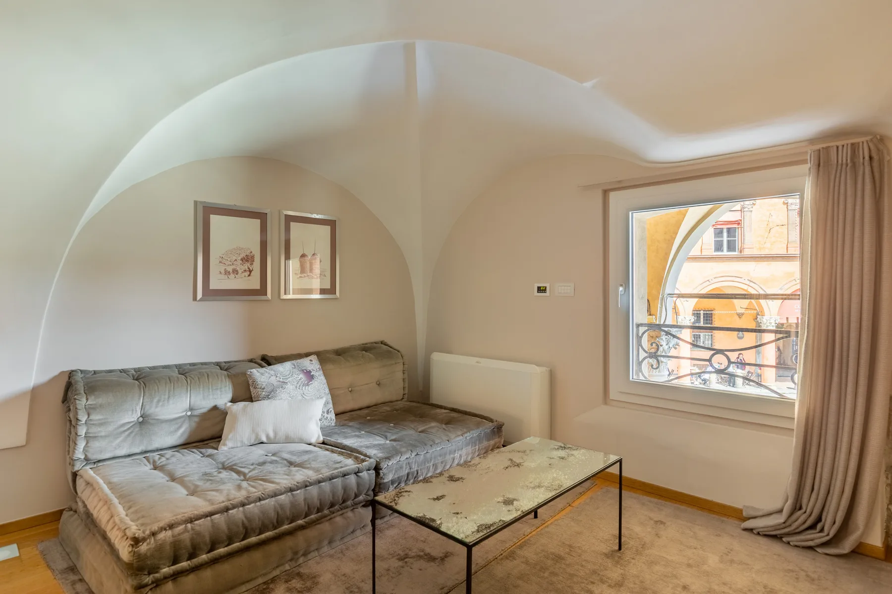 Una sala de estar con sofá seccional, mesa de centro y una ventana con vista a la calle.