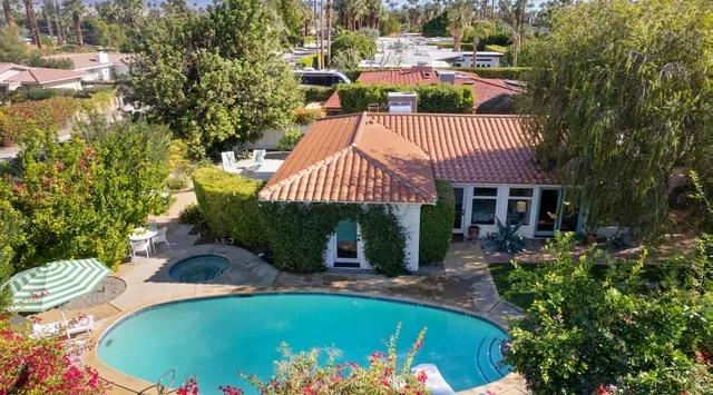 Vista aérea de una casa y una piscina rodeadas de árboles.