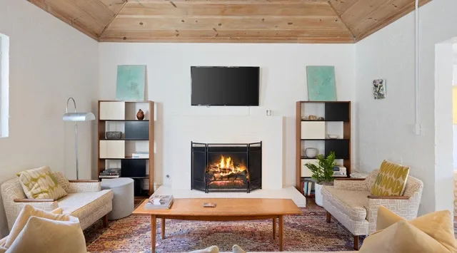 Una sala de estar con chimenea, televisor y asientos alrededor de una mesa de centro.