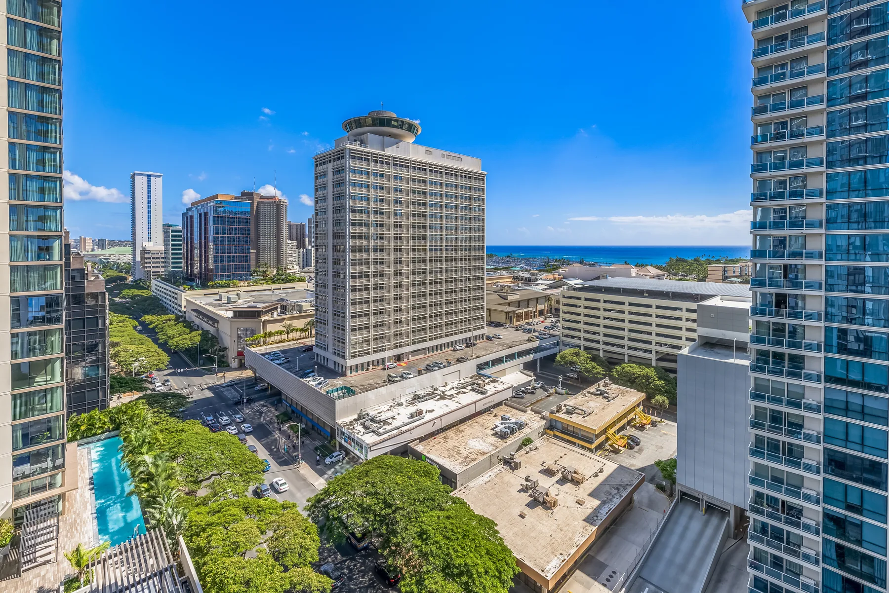A city skyline with high-rise buildings and the ocean visible in the distance.