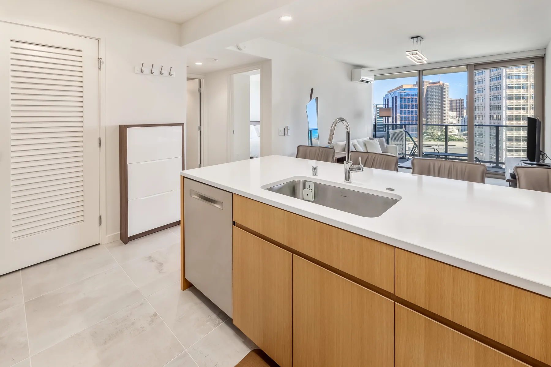 A bright kitchen features a large island with a sink and views through wide windows.