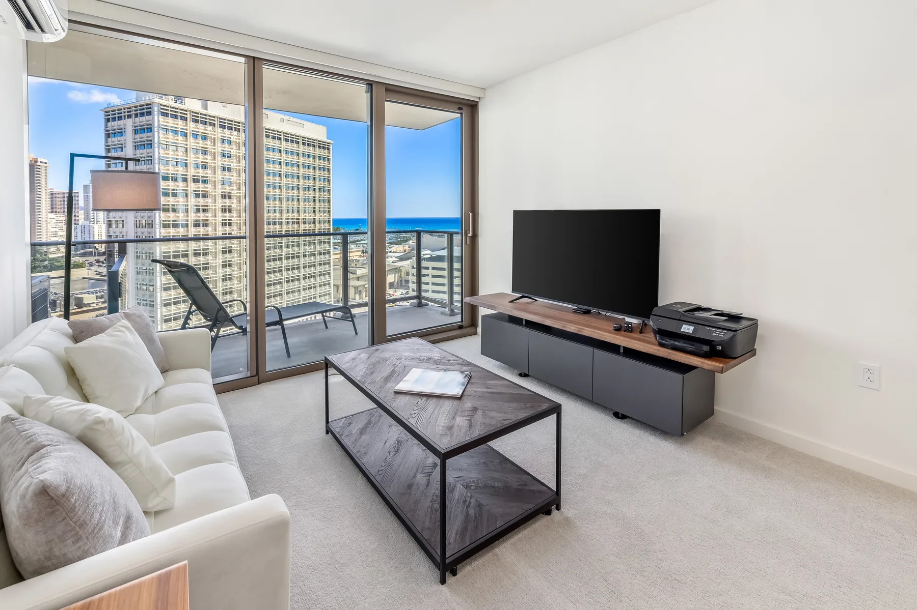 A living room with a television and glass doors opening onto a balcony.