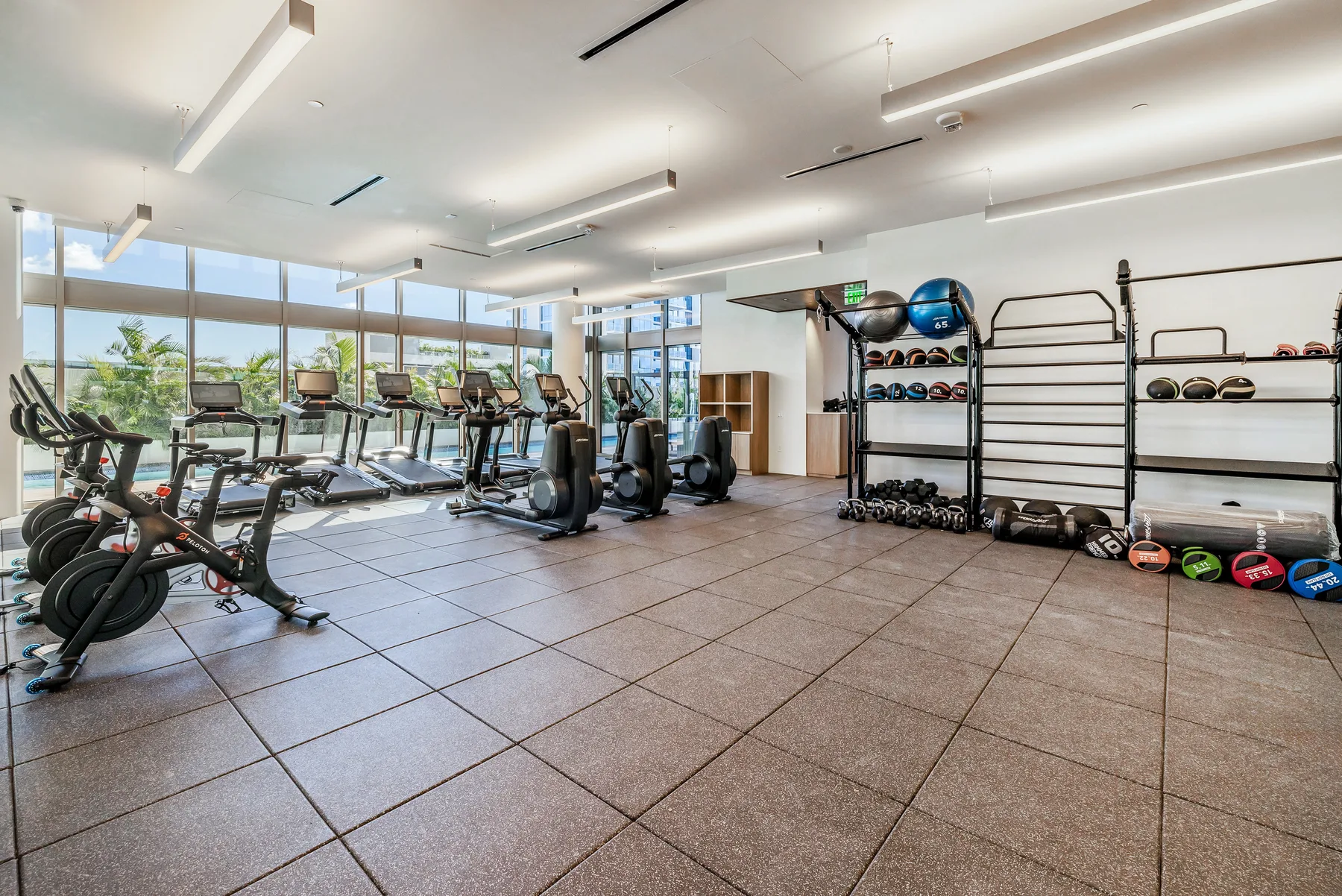 A bright fitness room with exercise machines and open floor space.