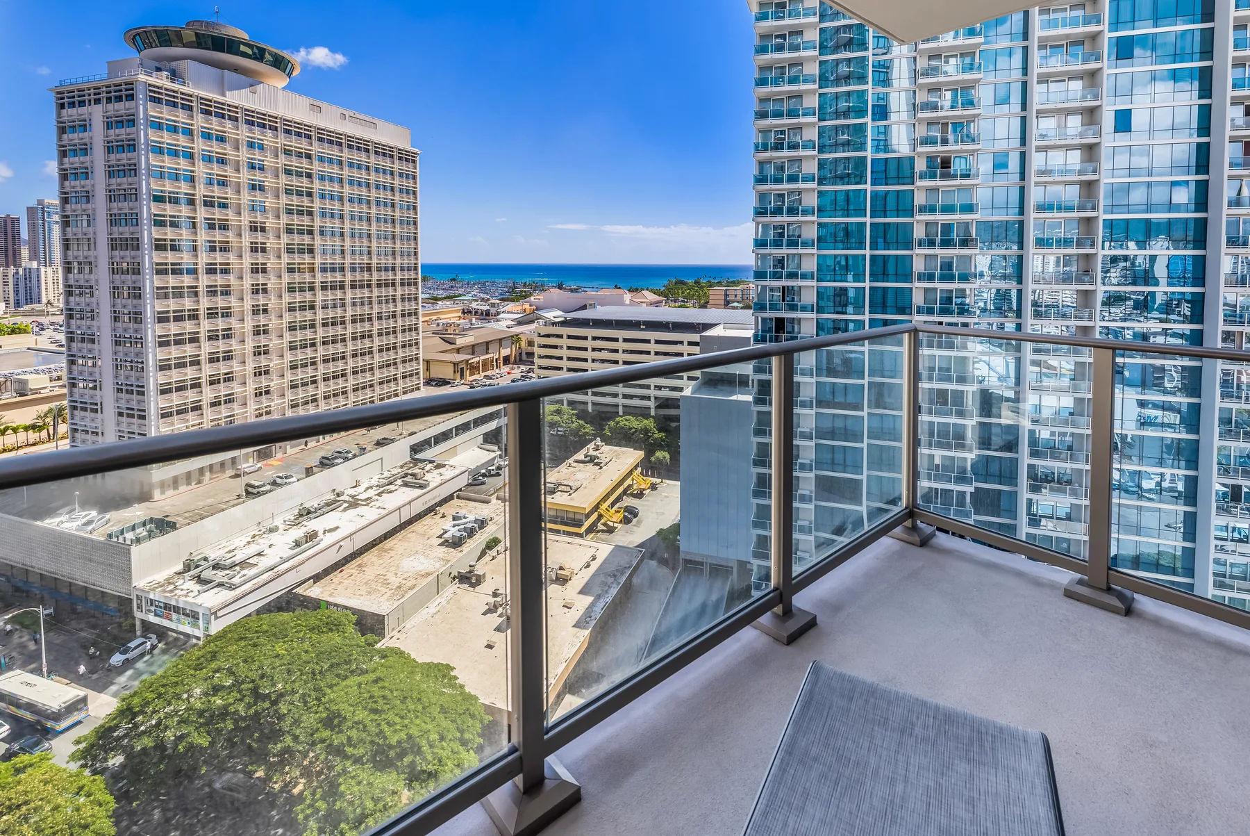 A balcony overlooks nearby high-rise buildings and a strip of ocean.