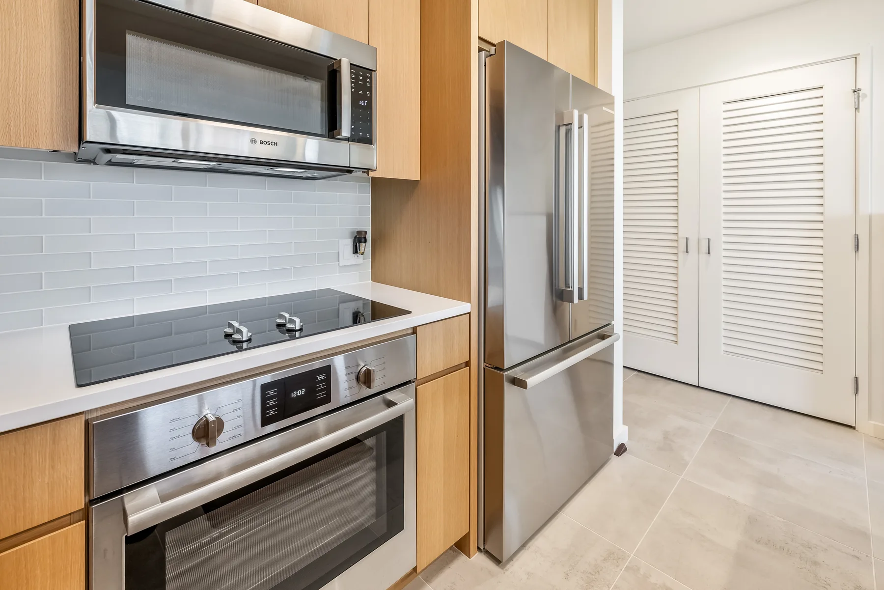 A modern kitchen with stainless steel appliances and light wood cabinetry.