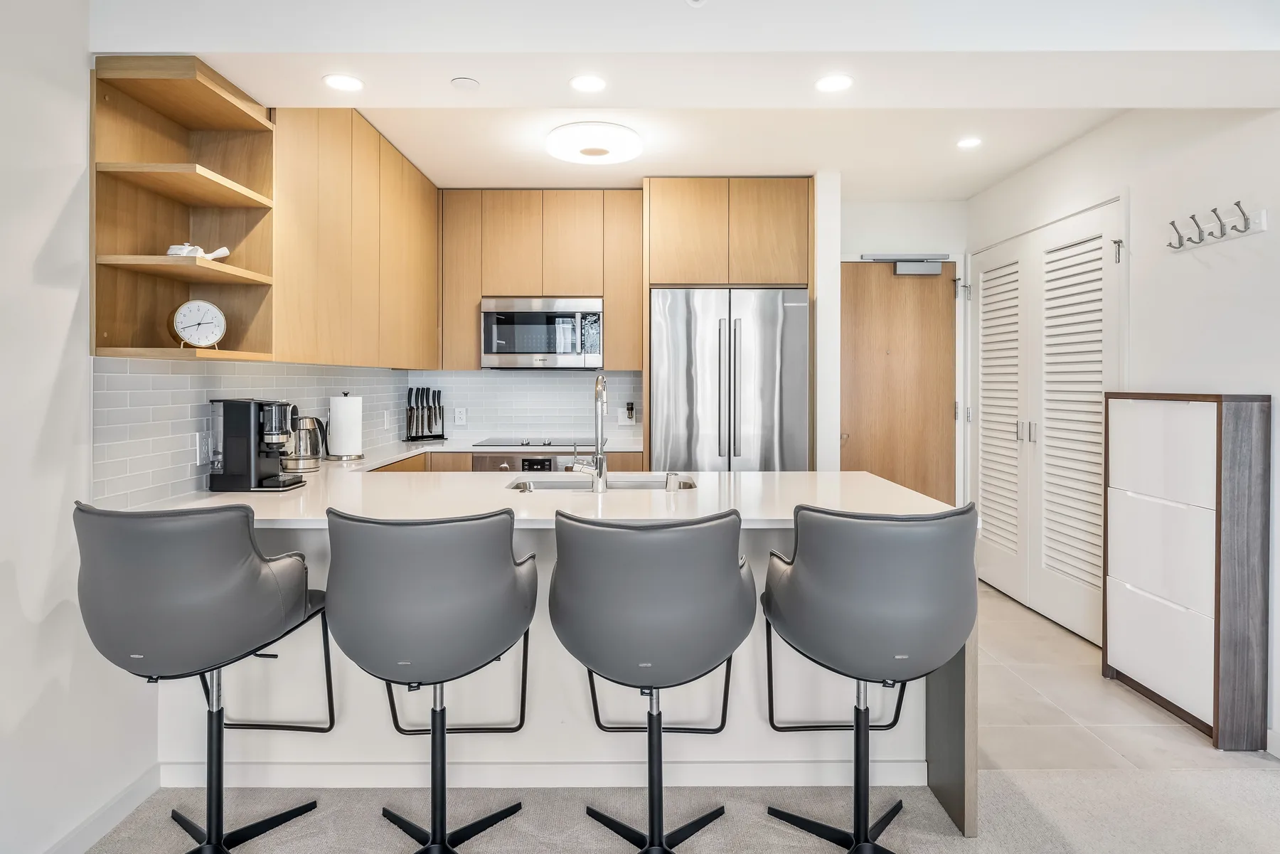 A bright kitchen with a long island and several bar stools.