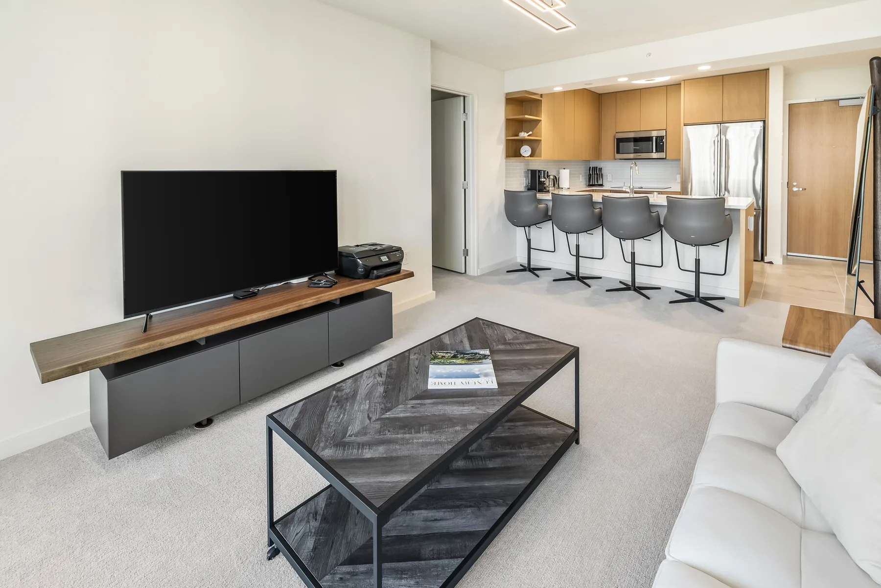 A bright living room opens onto a kitchen with a breakfast bar.